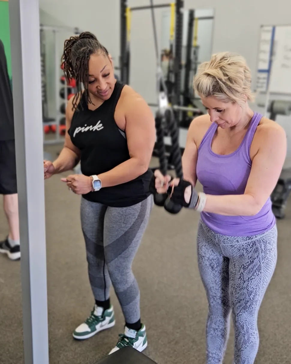 A VSF coach guiding a member through a strength exercise